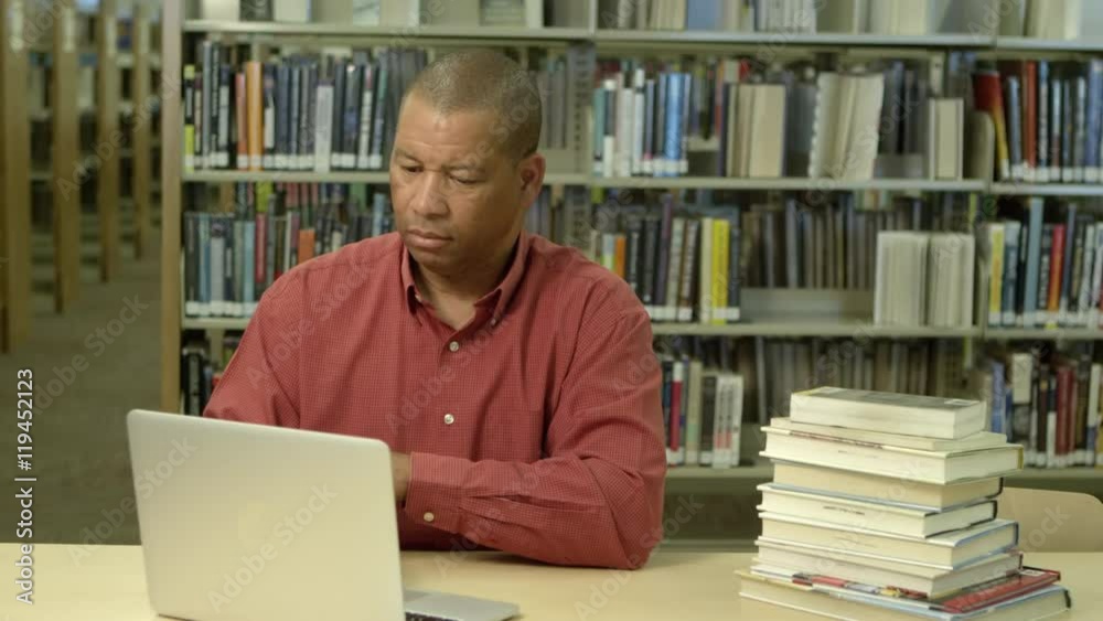 African american man using laptop in library African american man using laptop in library