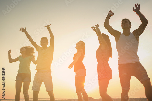 smiling friends dancing on summer beach