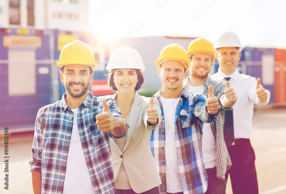 group of smiling builders in hardhats outdoors group of smiling builders in hardhats outdoors