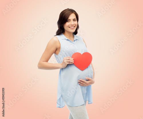 happy pregnant woman with red heart touching belly
