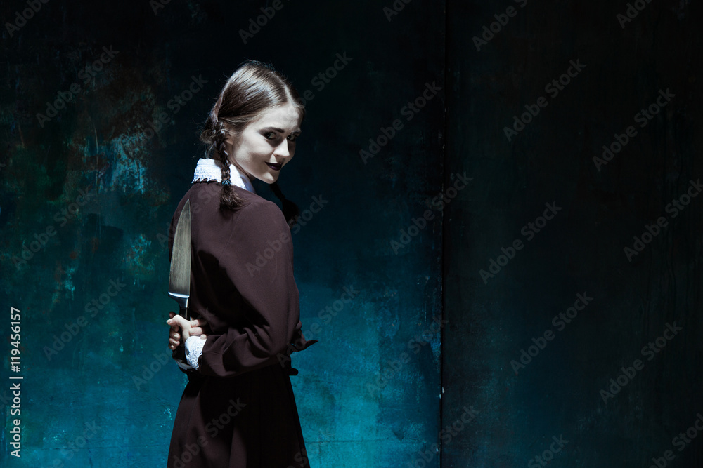 Fototapeta premium Portrait of a young girl in school uniform as killer woman