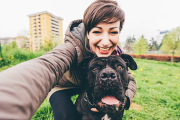 Young beautiful caucasian woman in a park outdoor taking selfie with her dog - happiness, friendship concept