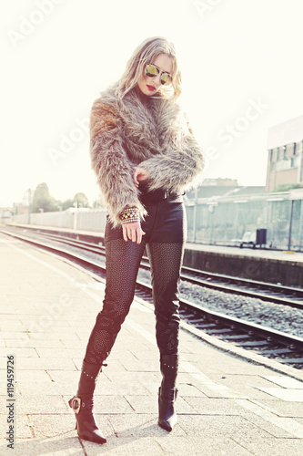 jeune femme blonde habillé mode style années 1980 en fourrure sur quai de gare 
