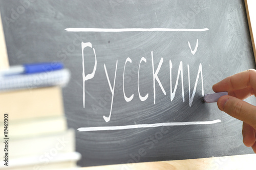 Hand writing on a blackboard in a Russian class. Some books and school materials. photo
