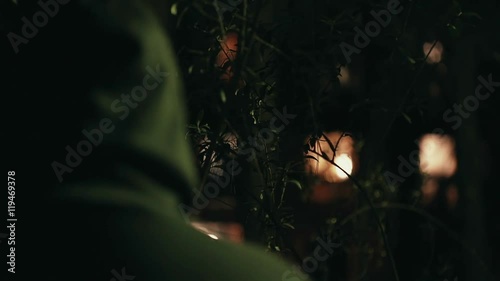 Hooded stalker stalking apartment from a distance at night,rack focus