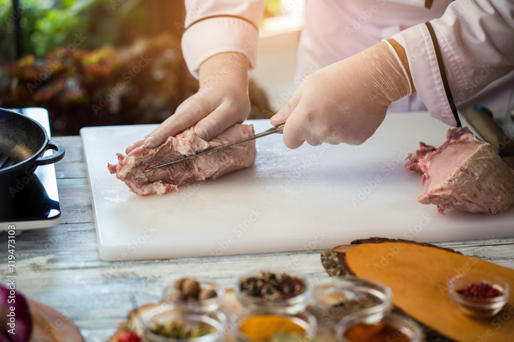 Knife is cutting raw meat. Cook's hands in gloves. Chef is cooking pork.  Ingredient of high-calorie dish. Stock Photo | Adobe Stock