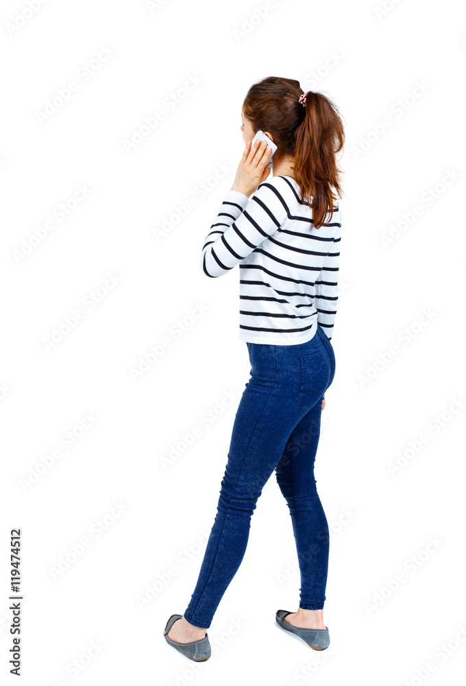 back view of a woman talking on the phone. backside view of person. Girl in a striped sweater and is talking on the phone. back view of a woman talking on the phone. backside view of person. Girl in a striped sweater and is talking on the phone.