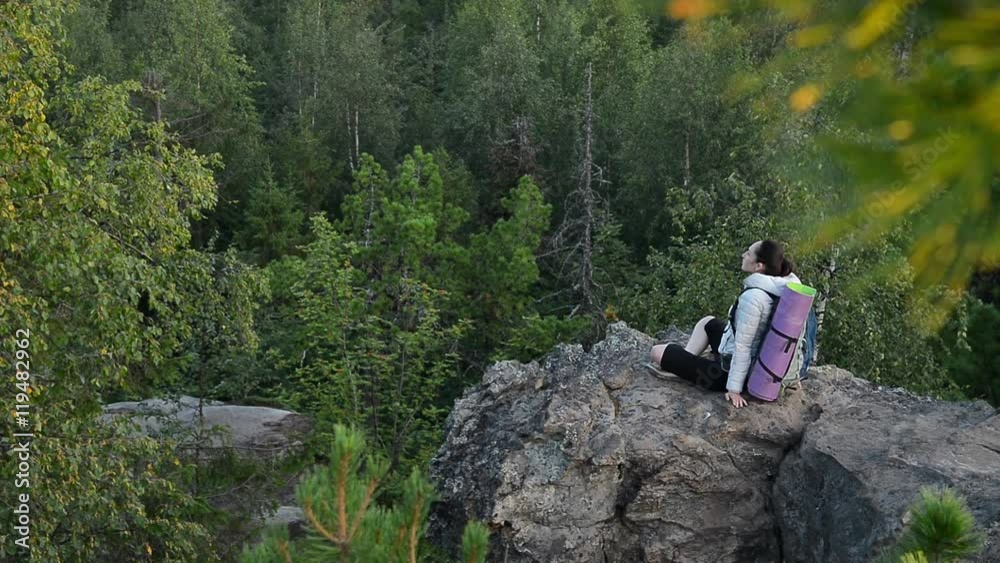 Young woman backpacker sitting on big rock and relax ar sunrise Young woman backpacker sitting on big rock and relax ar sunrise