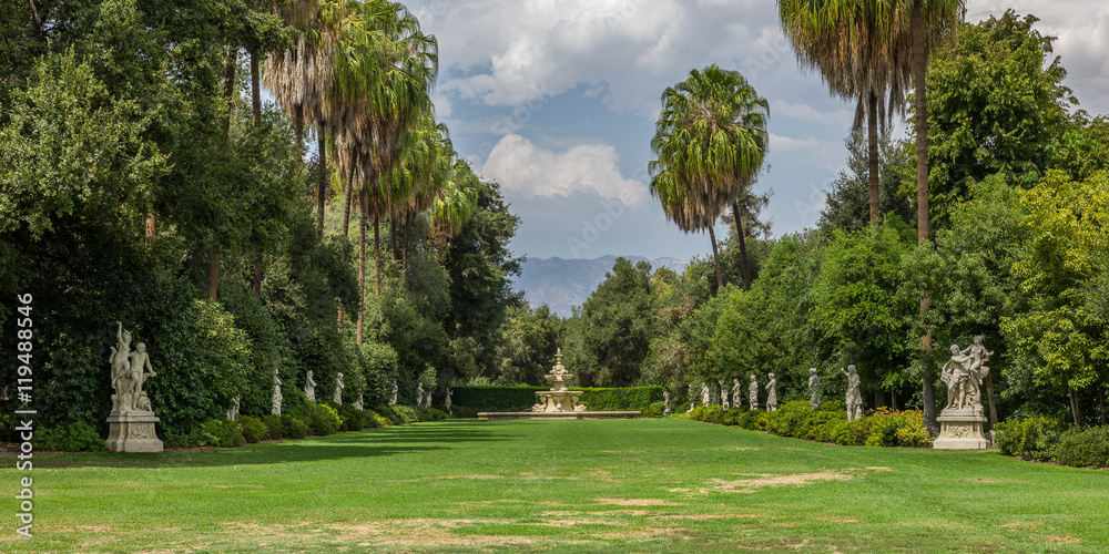 Large garden lined with trees with sky and mountains view