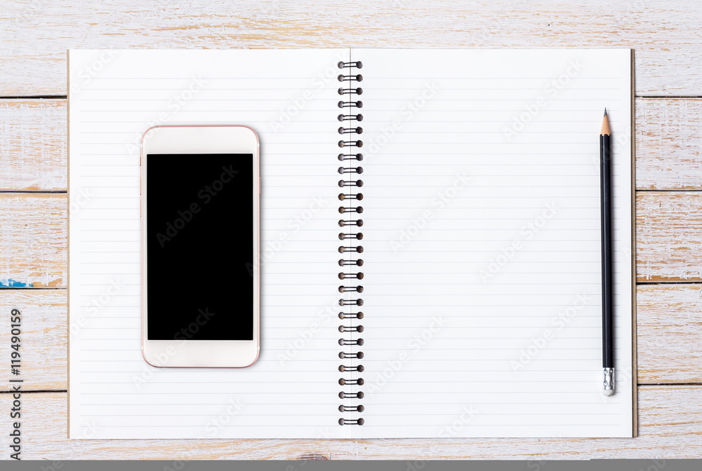 Open Notebook and smart phone on wood table for background Open Notebook and smart phone on wood table for background