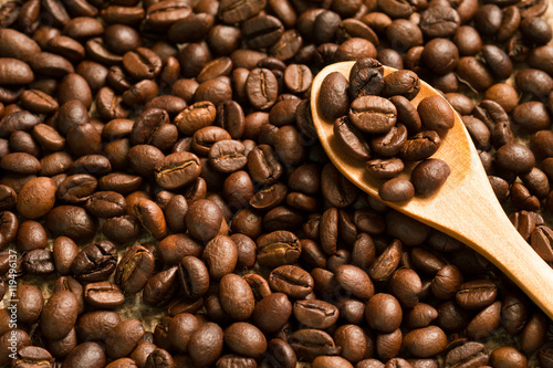 Coffee beans on a wooden spoon and on coffee beans background