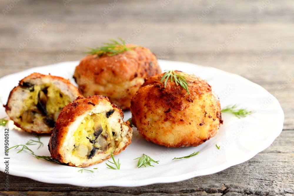 Fried meat patties stuffed with cheese and fried mushrooms on plate on wooden background. Homemade stuffed patties prepared from minced meat. Closeup Fried meat patties stuffed with cheese and fried mushrooms on plate on wooden background. Homemade stuffed patties prepared from minced meat. Closeup