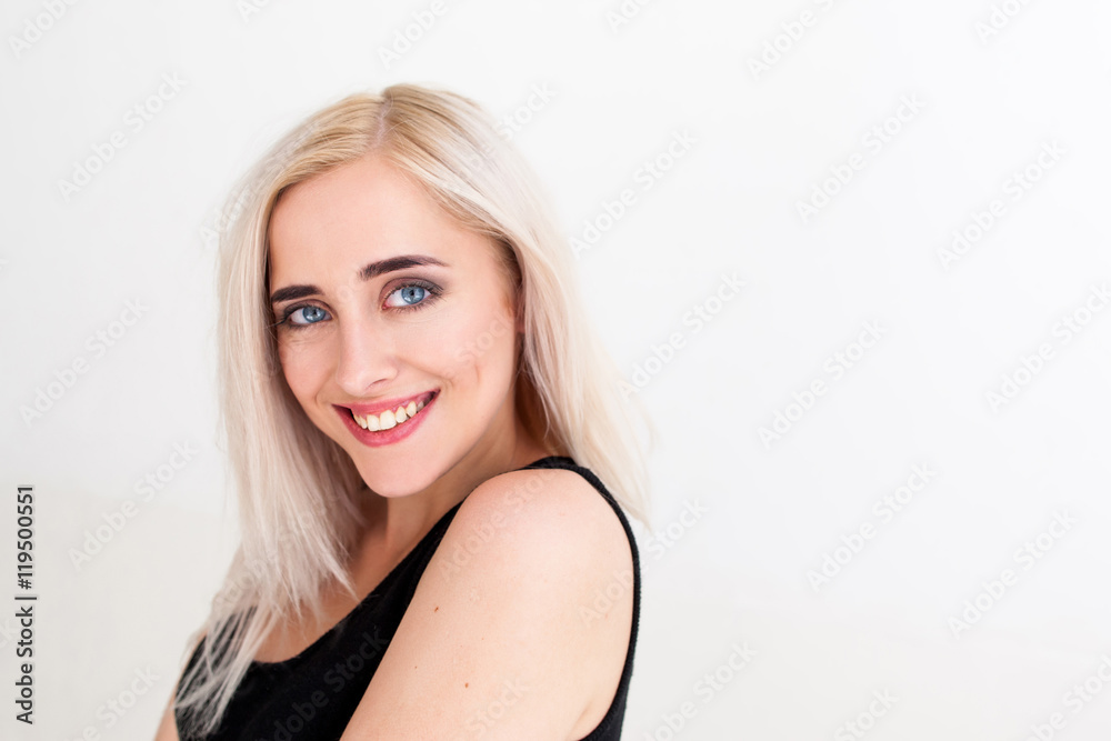 Attractive smiling blonde on white, copy space. Portrait of young beautiful half-turned blue-eyed woman, looking at camera, white background Attractive smiling blonde on white, copy space. Portrait of young beautiful half-turned blue-eyed woman, looking at camera, white background