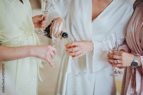 Bride and bridesmaids are hugging and are holding champagne glasses