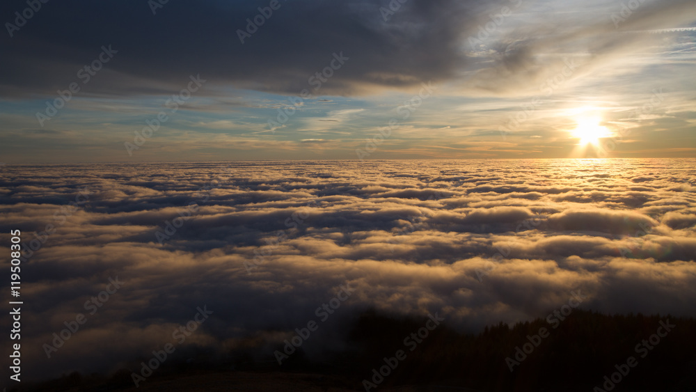 Landscape with the sun setting behind clouds and fog