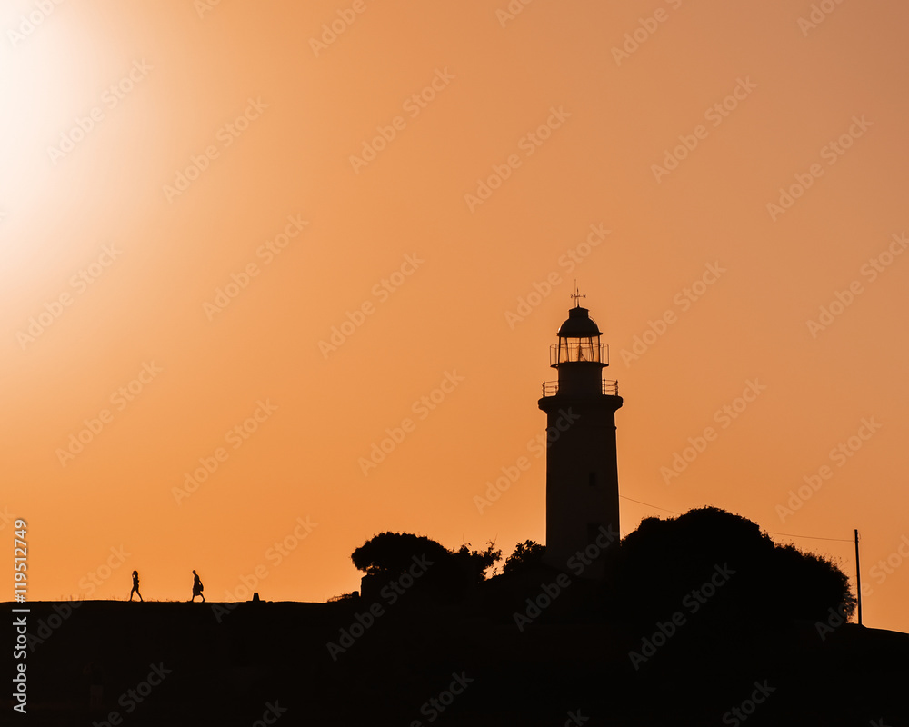 Lighthouse silhouetted against an orange sunset