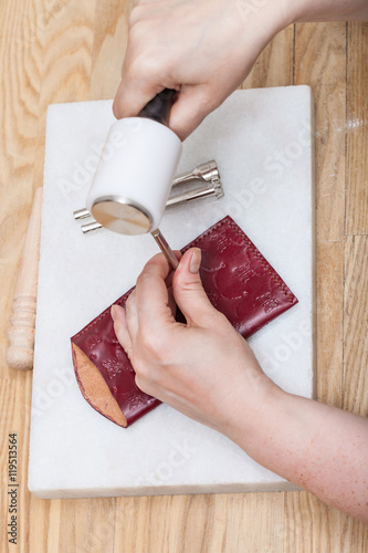 craftsman corrects stamping of leather pouch photo