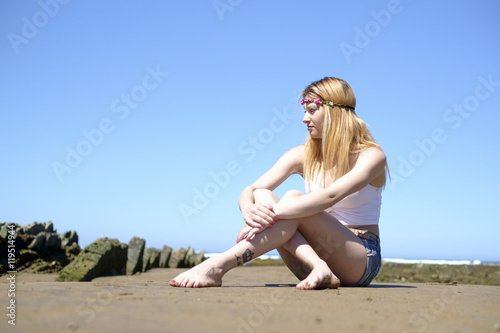 Portrait of young woman hippie style sitting in the beach.