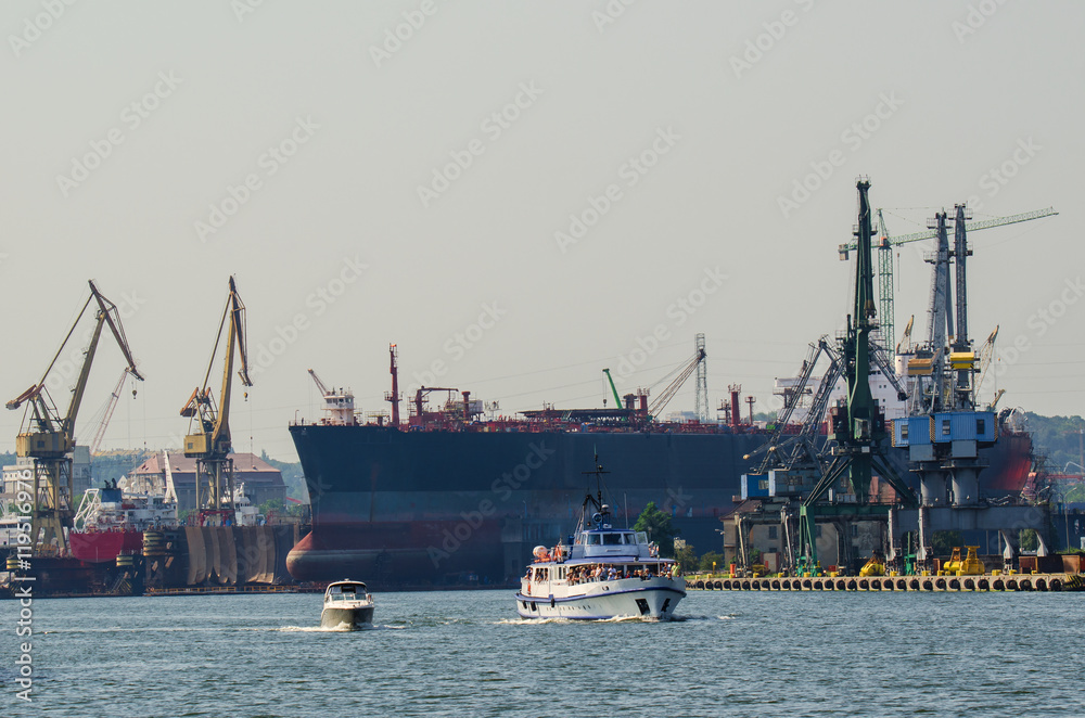 GDANSK SHIPYARD. Built ship dock and cranes at the Gdansk shipyard. Ship walking on the background of the shipyard GDANSK SHIPYARD. Built ship dock and cranes at the Gdansk shipyard. Ship walking on the background of the shipyard