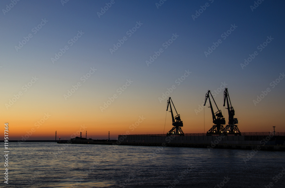 SEA PORT OF GDYNIA AT DAWN. Cloudless sky, harbor cranes and a quay at the port of Gdynia at dawn