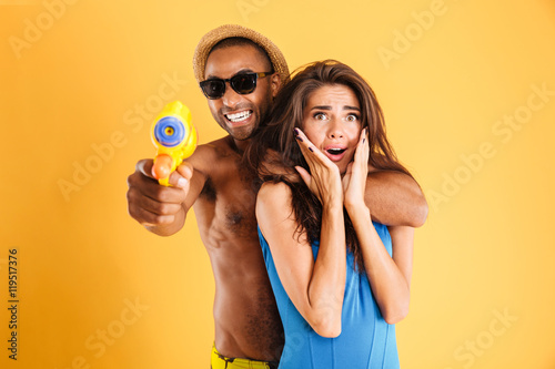 Young happy multiracial couple having fun playing with water guns