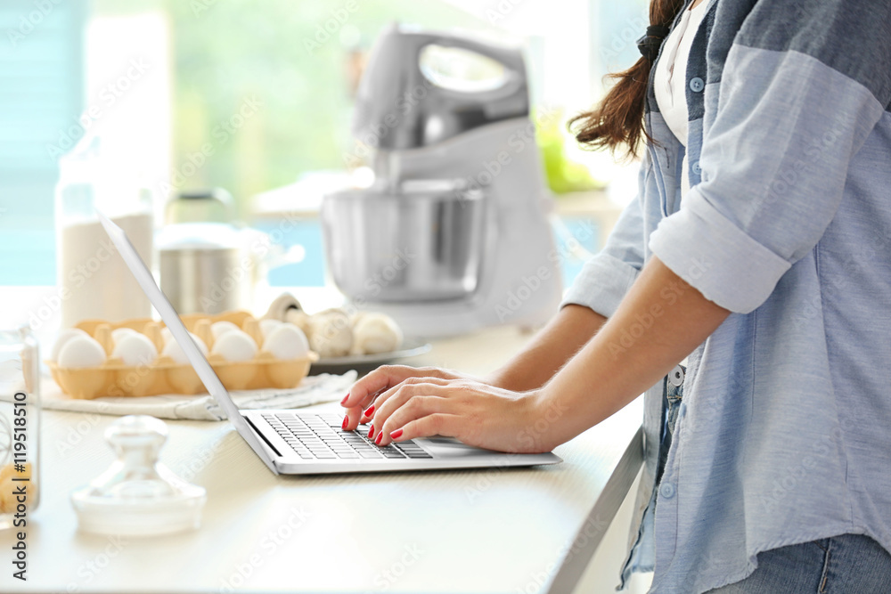 Girl with laptop on kitchen. Food blogger concept