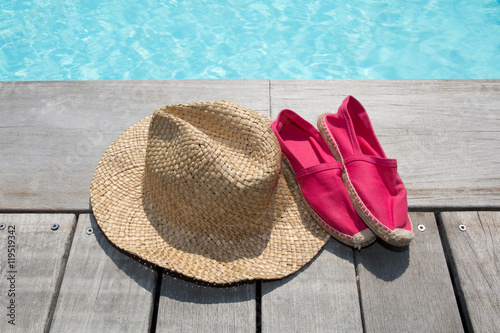 Summer background with hat shoes on the wooden deck and pool