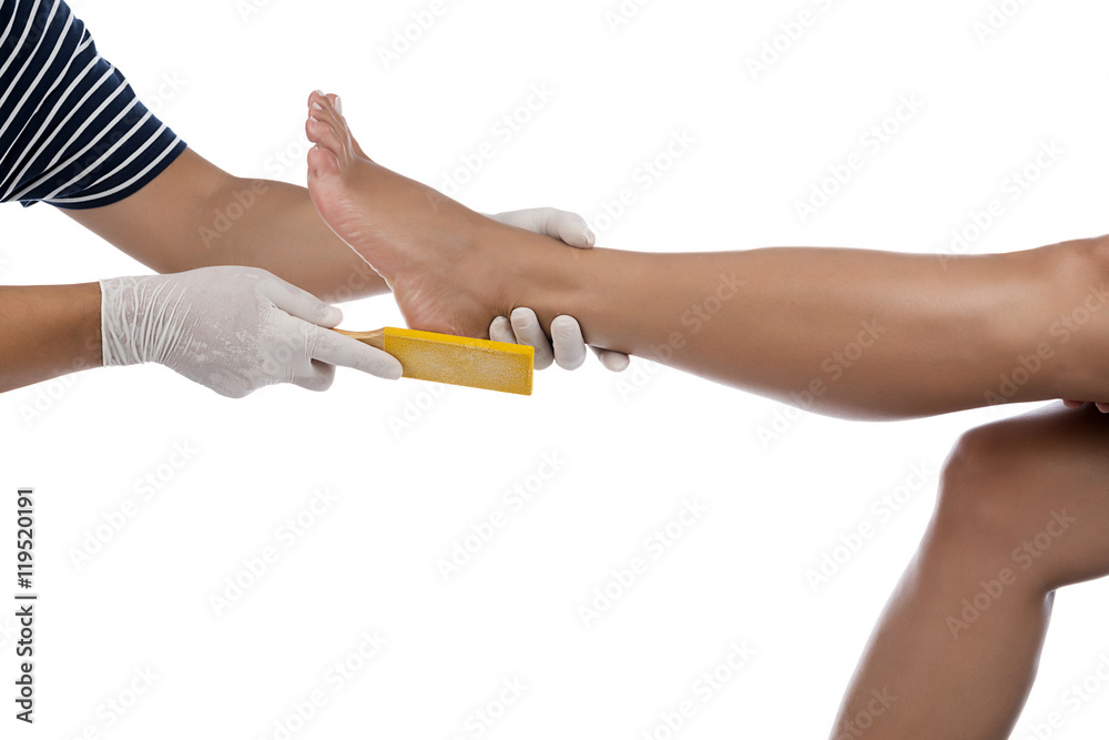 Beautician removing dead skin from the foot of a beautiful woman.   