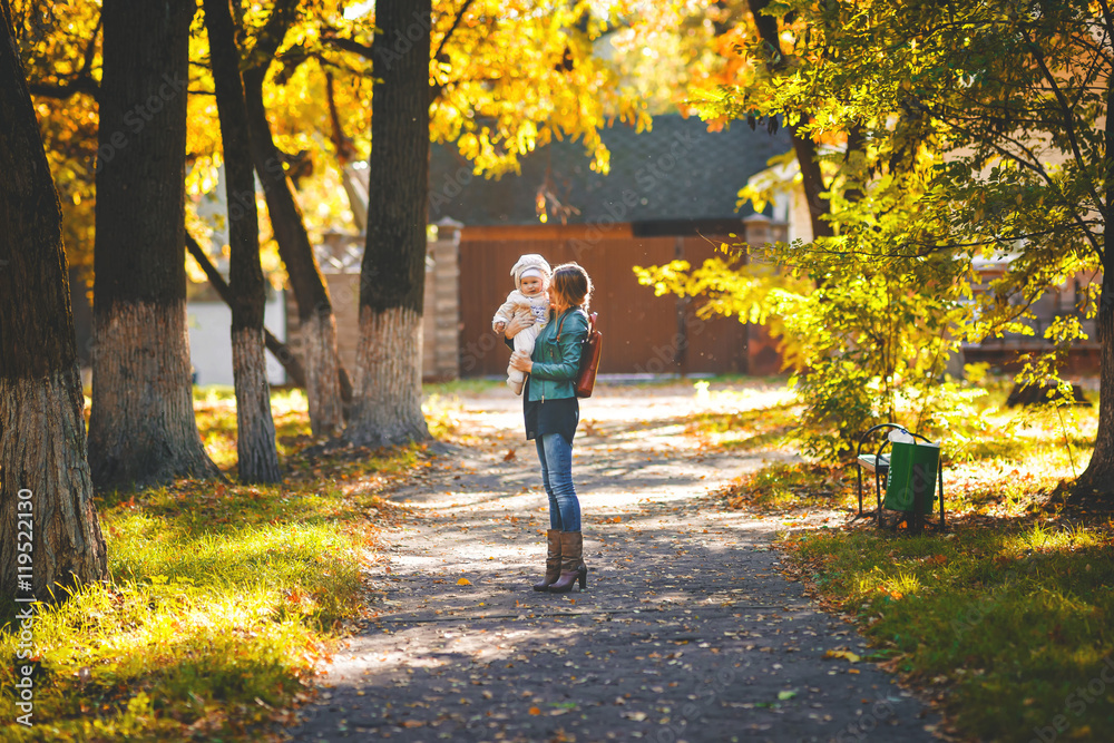 Young mother holding her daughter in the autumn park Young mother holding her daughter in the autumn park