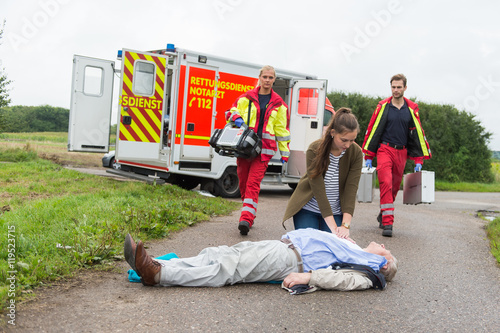 Rettungskräfte treffen an Einsatzort ein während Ersthelferin erste Hilfe leistet photo