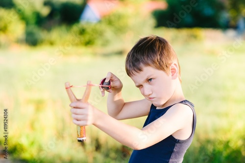 Valokuvatapetti Little boy playing with slingshot