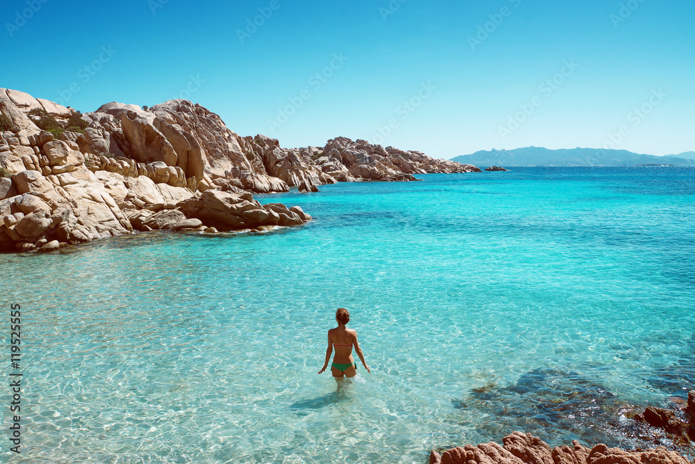 Frau steht in glasklarem Wasser einer Bucht