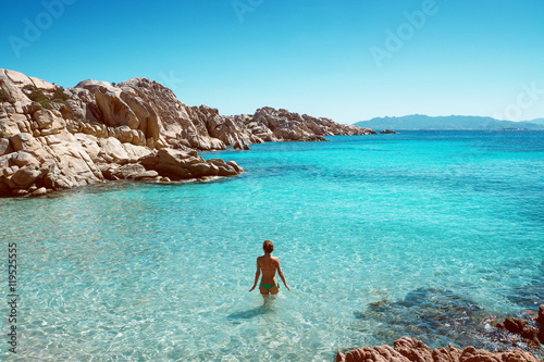 Frau steht in glasklarem Wasser einer Bucht photo