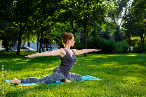 Young woman doing yoga exercises in the summer city park. © nazarovsergey
