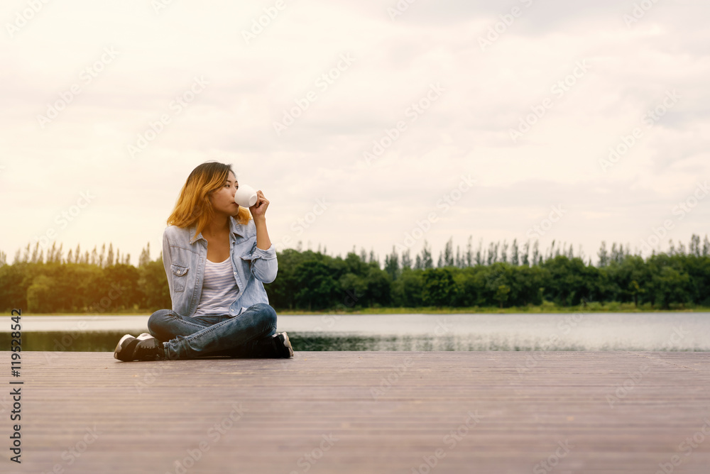 Girl drinks tea on wood balcony by river Girl drinks tea on wood balcony by river