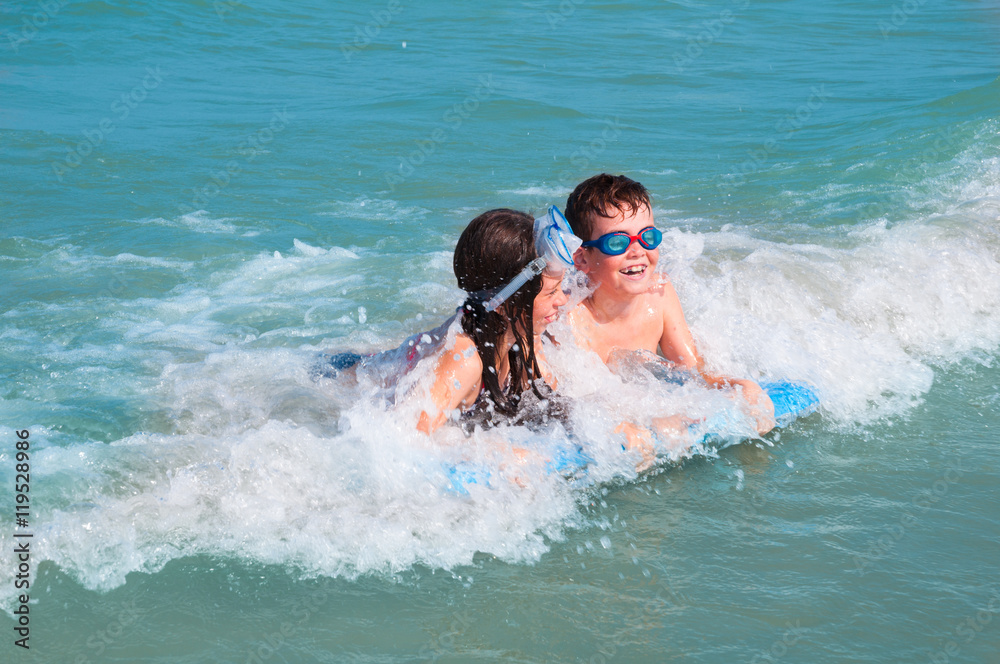 Two kids swimming with surf board