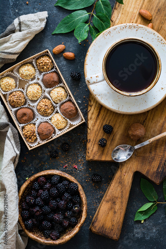 Chocolate truffles, cup of black coffee and fresh blackberries. Still life coffee time. Top view, vertical