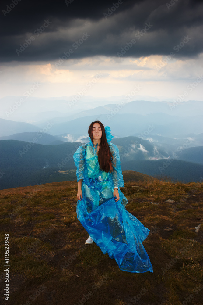 Girl in raincoat. Portrait of beautiful girl on top of mount Hoverla. Mountain landscape. Rain clouds, dramatic mood. Closed eyes. Climbing to top of mountain Girl in raincoat. Portrait of beautiful girl on top of mount Hoverla. Mountain landscape. Rain clouds, dramatic mood. Closed eyes. Climbing to top of mountain