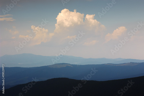 Mountain landscape in haze. Beautiful clouds in sky above mountain ridge. Stormy weather. Panorama