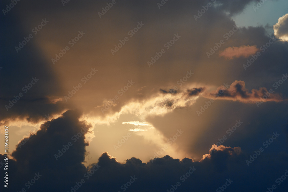 Beautiful evening skyscape. Sun's rays shine through hole in clouds after rain. Sky, lit by setting sun. Natural background