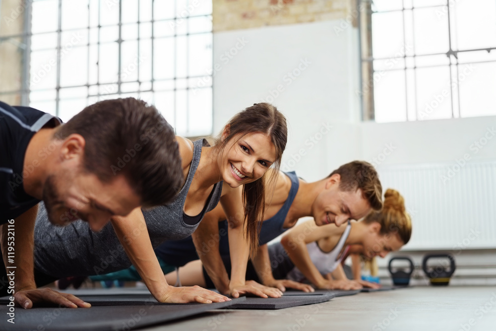 lachende frau trainiert in einer gruppe im fitness-studio - obrazy, fototapety, plakaty 