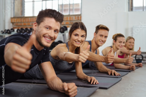 gruppe im fitness-studio zeigt daumen hoch