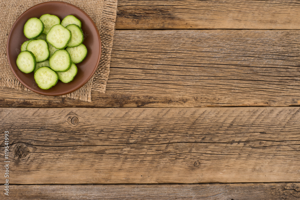 sliced cucumbers in a brown plate on old wooden table. sliced cucumbers in a brown plate on old wooden table.