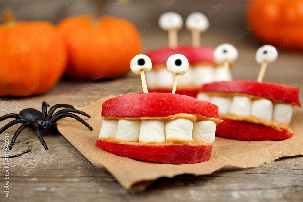 Fototapeta premium Healthy Halloween apple, marshmallow, peanut butter monster teeth on a rustic wooden background