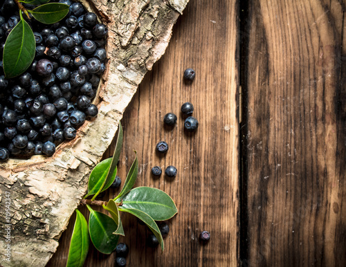 Blueberries with leaves . On wooden background.