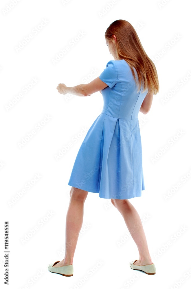 back view of standing girl pulling a rope from the top or cling to something. Isolated over white background. Skinny girl in a blue dress and pulls the load on the rope.