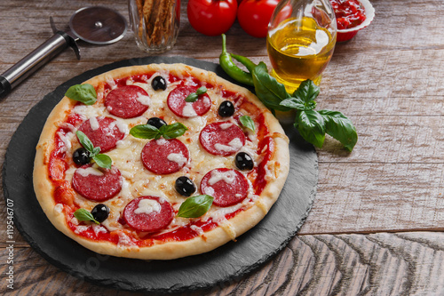 pizza with salami tomato and cheese on a wooden surface