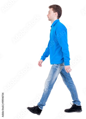 Back view of going handsome man. walking young guy . Curly boy in blue sweater goes sideways.