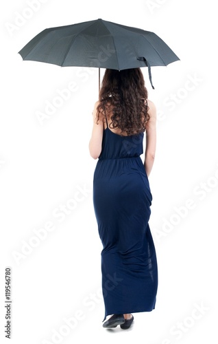 young woman in dress walking under an umbrella. dark curly girl in blue evening dress went off under a black umbrella. © ghoststone
