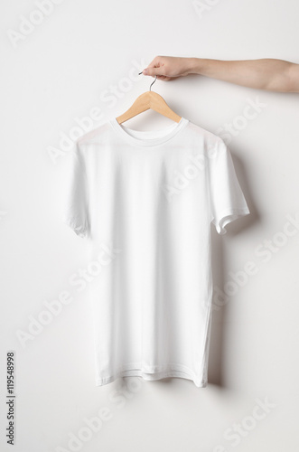 фотографія Men's Crew Neck T-Shirt Mock-Up - Man holding a white t-shirt on a wooden clothe